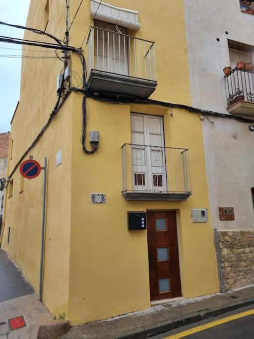 un bâtiment jaune avec deux fenêtres et une porte dans l'établissement Traditional Spanish Town House, à Móra d'Ebre