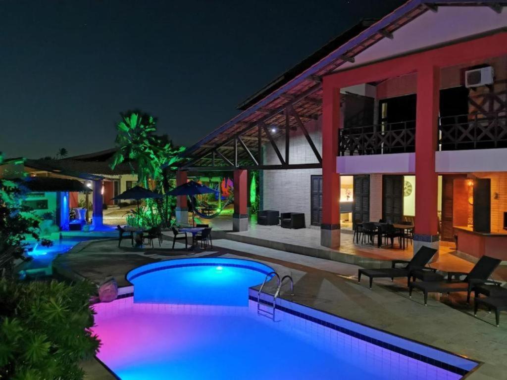 een zwembad met blauwe lichten voor een gebouw bij Pousada Villa Flamboyant in Beberibe