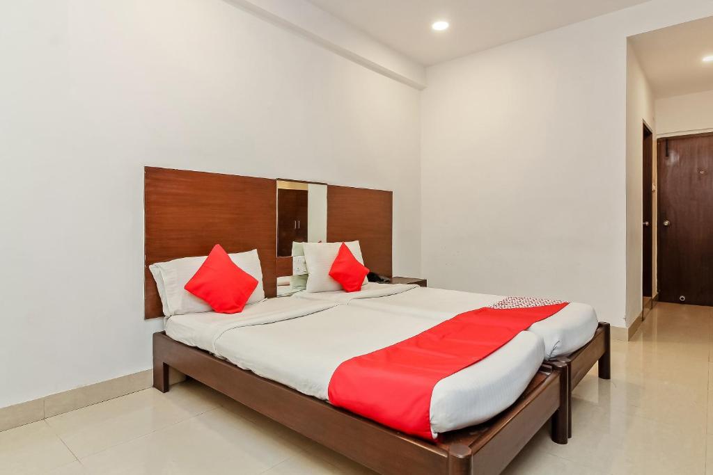 1 dormitorio con 1 cama grande con almohadas rojas en Collection O Hotel Happy Stay Near Hyderabad Central en Ameerpet