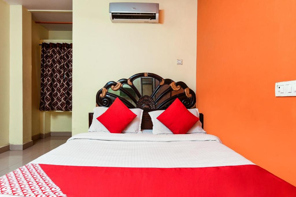 - une chambre avec un lit doté d'oreillers rouges et blancs dans l'établissement OYO Sindhura Guest House, à Raspari Palao