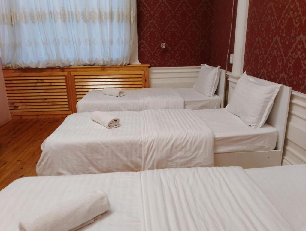 three beds in a hotel room with white sheets at Nice Trip in Yunusobod