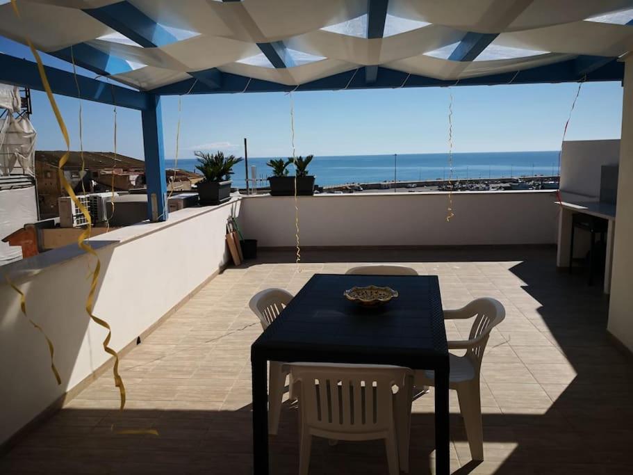 een tafel en stoelen op een balkon met uitzicht op de oceaan bij Il terrazzo sul porto in Sciacca