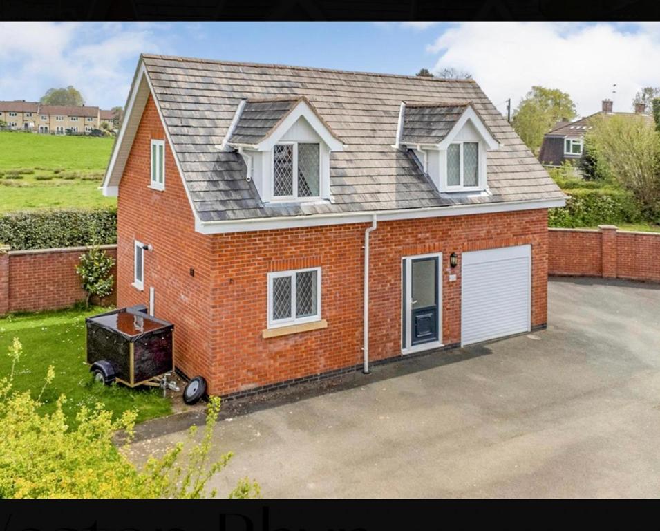 una casa in mattoni rossi con un garage bianco di The Little House, Oswestry a Chirk