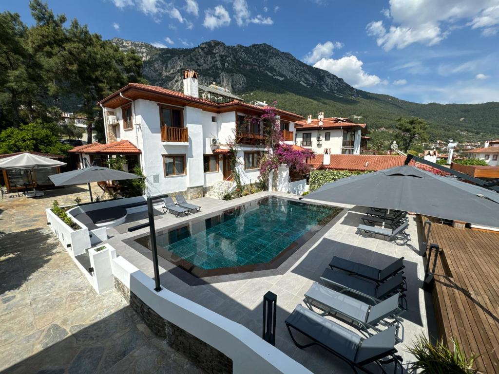 a house with a swimming pool and an umbrella at Tomsan Suites & Villas Akyaka in Akyaka
