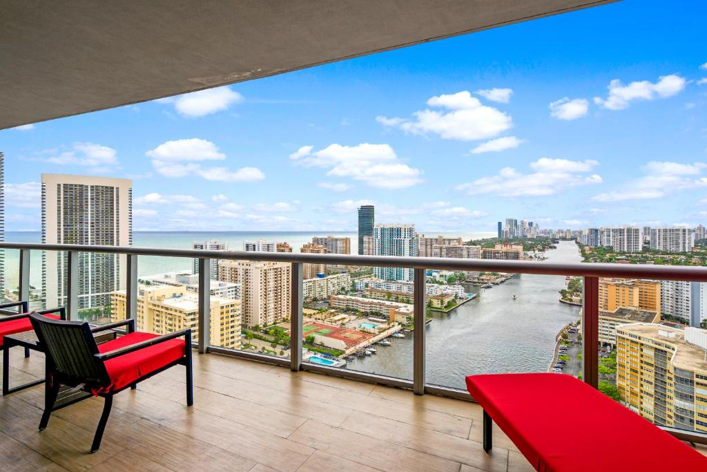 a balcony with red chairs and a view of the ocean at Ocean Views - Pool & Gym - Pet Friendly - Close to Beach in Hallandale Beach