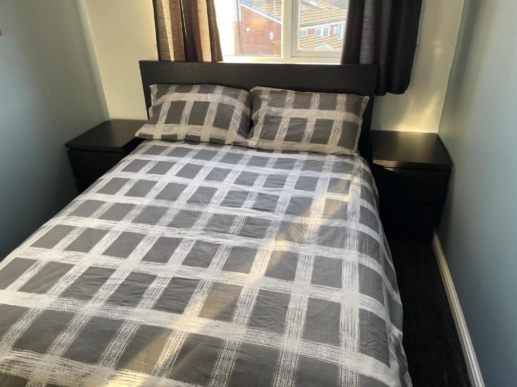 a bed with a plaid comforter and two pillows at Kilmarnock in Kilmarnock