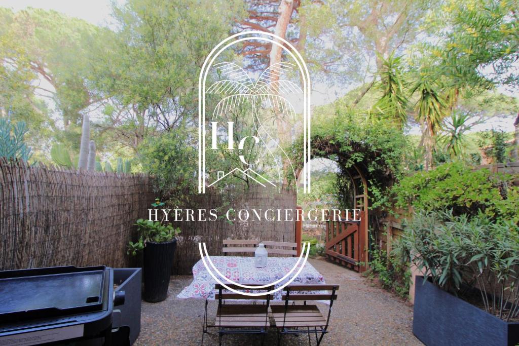 a table and chairs in a garden with a sign at Triplex Le Port d'Hyères-400m-CLIM WIFI PARKING BY HC in Hyères