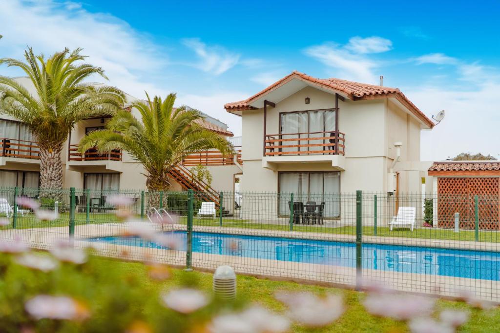 a house with a swimming pool and palm trees at Agua Marina - La Serena in La Serena