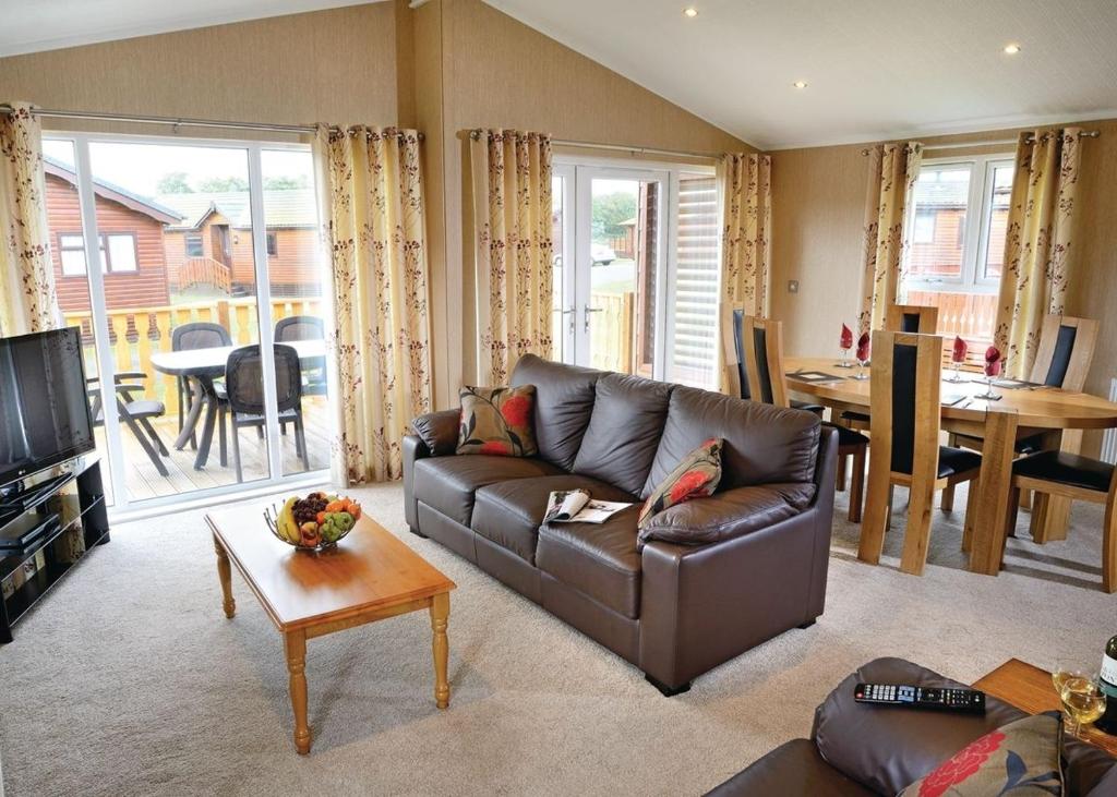 a living room with a leather couch and a table at South Lakeland Leisure Village in Hornby