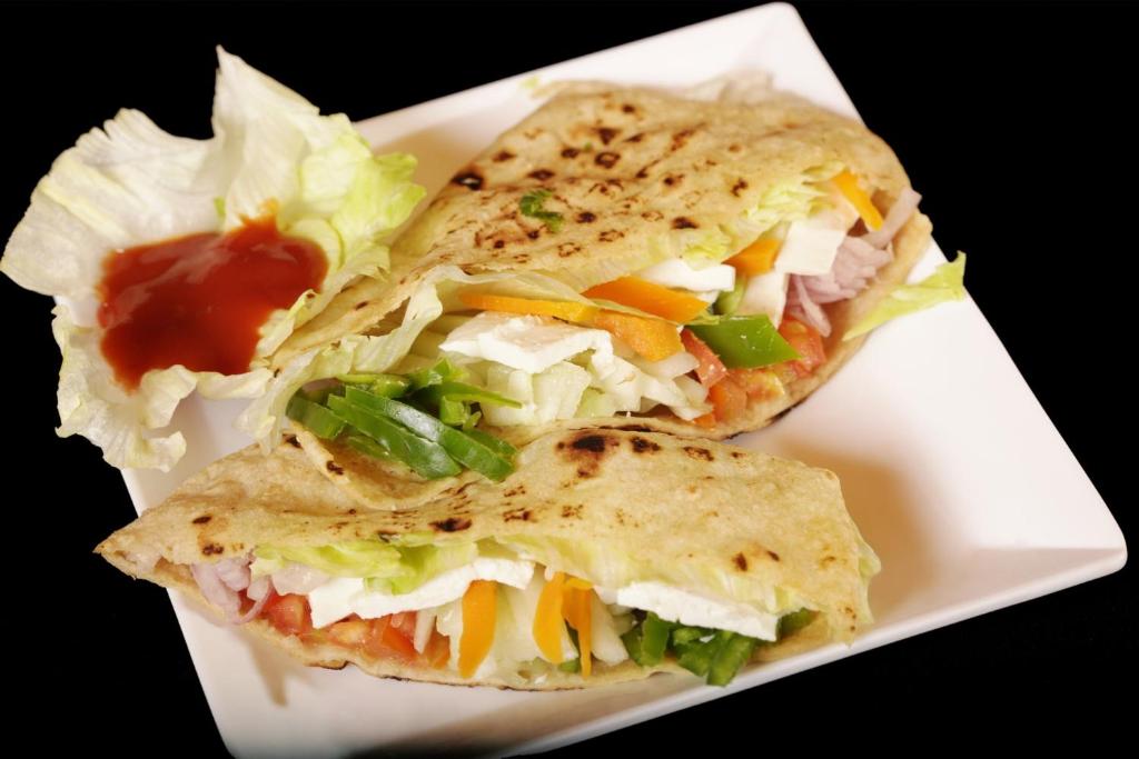 zwei Sandwiches auf einem weißen Teller mit Salat und Ketchup in der Unterkunft Hotel Rosewood Inn in Rājpur