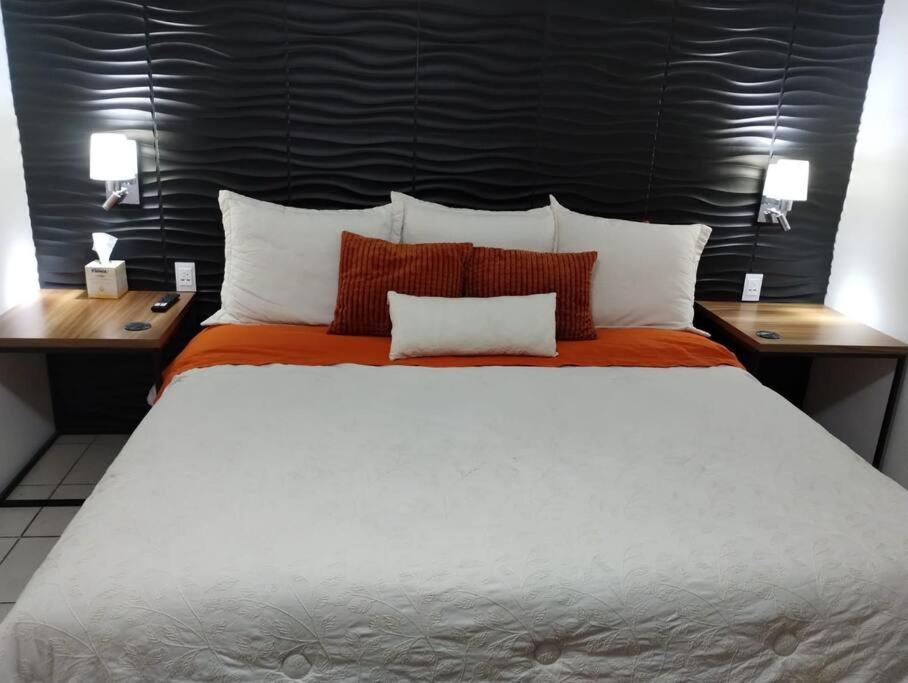 Casa Orquídea في غواذالاخارا: غرفة نوم بسرير ابيض كبير مع طاولتين