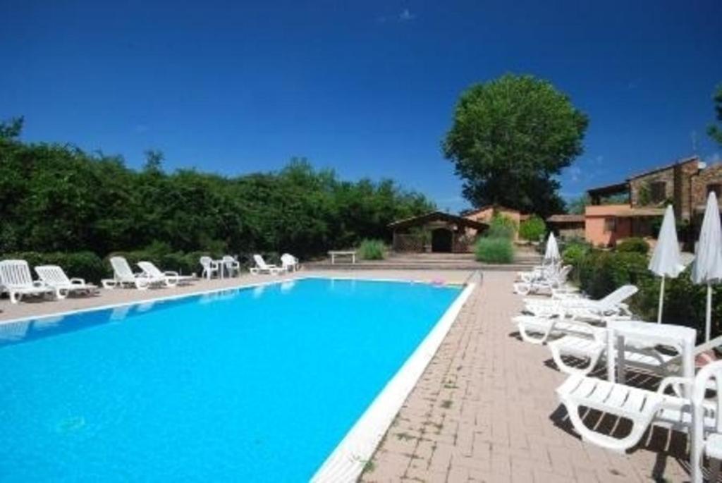 einen Pool mit weißen Liegestühlen und Sonnenschirmen in der Unterkunft Studio für 4 Personen  1 Kind ca 80 qm in Pievescola, Toskana Provinz Siena in Casole dʼElsa