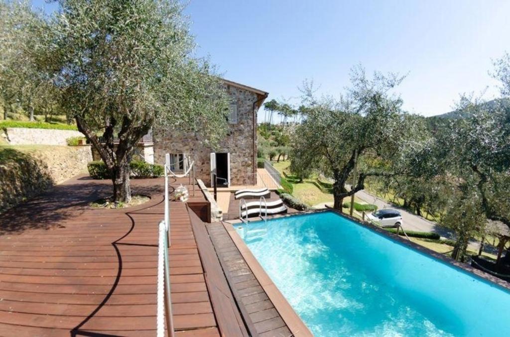 een buitenzwembad met bomen en een huis bij Ferienhaus mit Privatpool für 7 Personen ca 200 qm in Capannori, Toskana Provinz Lucca in Capannori
