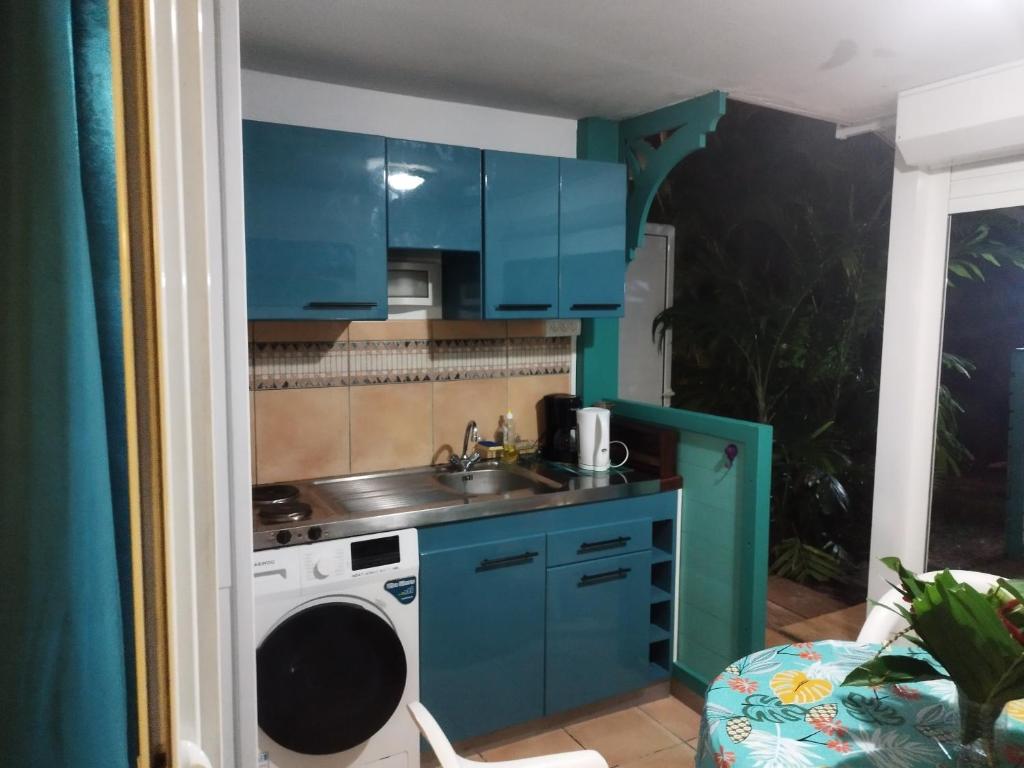 a kitchen with blue cabinets and a washing machine at studio francelu in Sainte-Anne