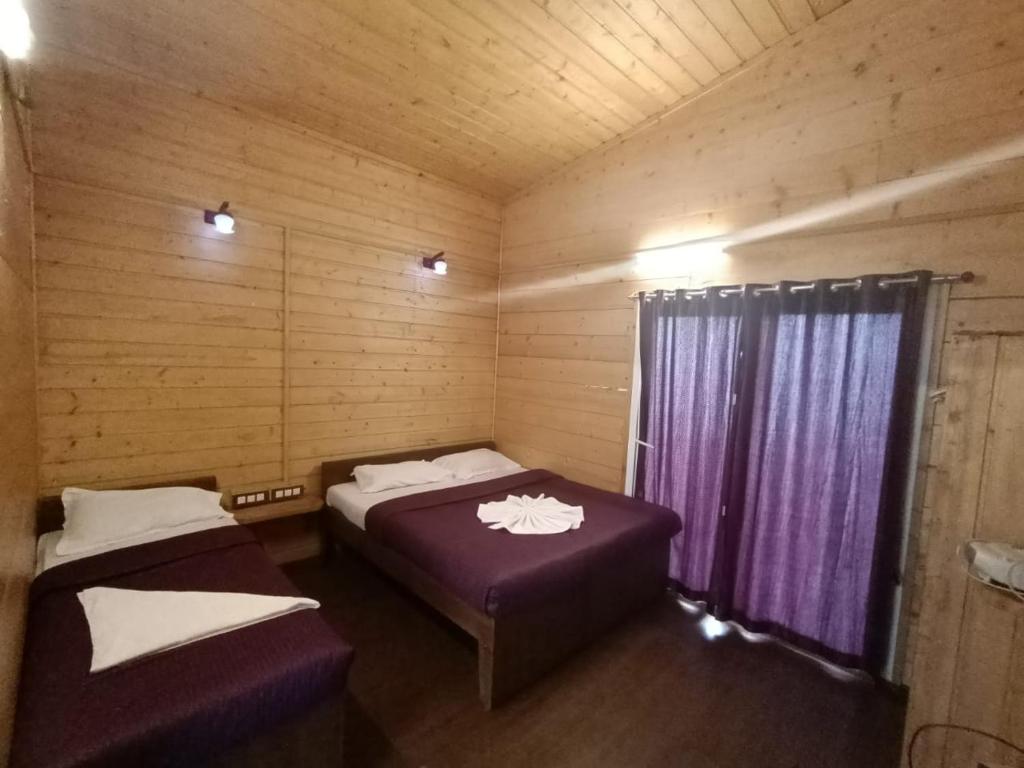 a room with two beds in a wooden cabin at Praveen Woodhouse and Homestay Kodaikanal Vattakanal in Kodaikānāl