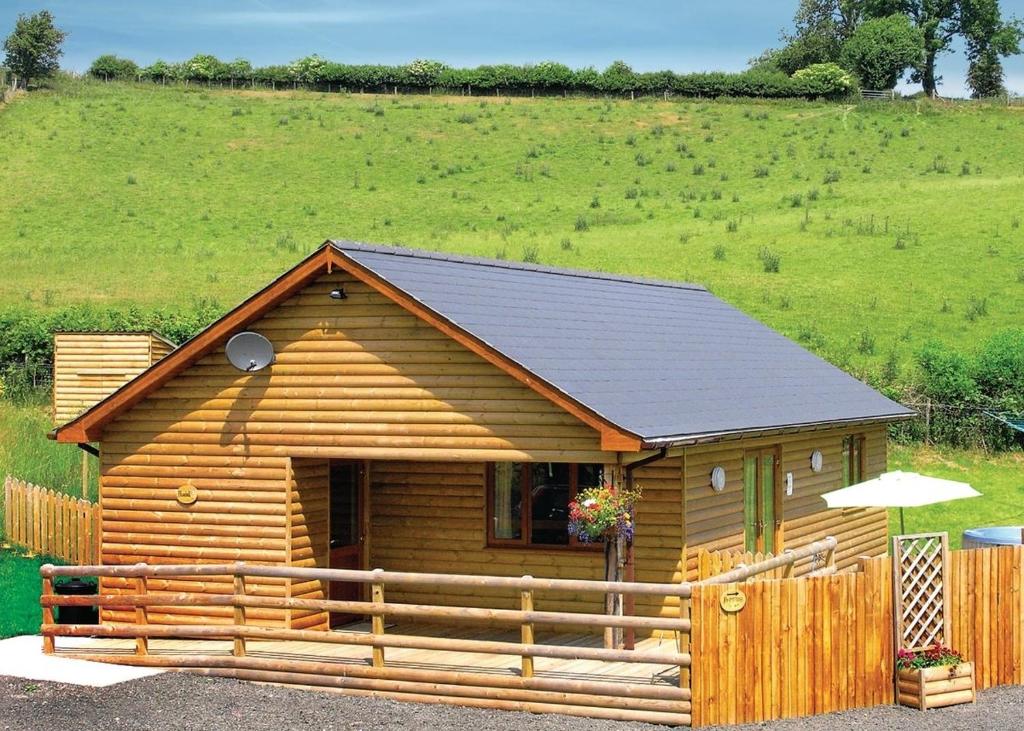 uma cabana de madeira com uma vedação num campo em Heartsease Lodges em Llanbister