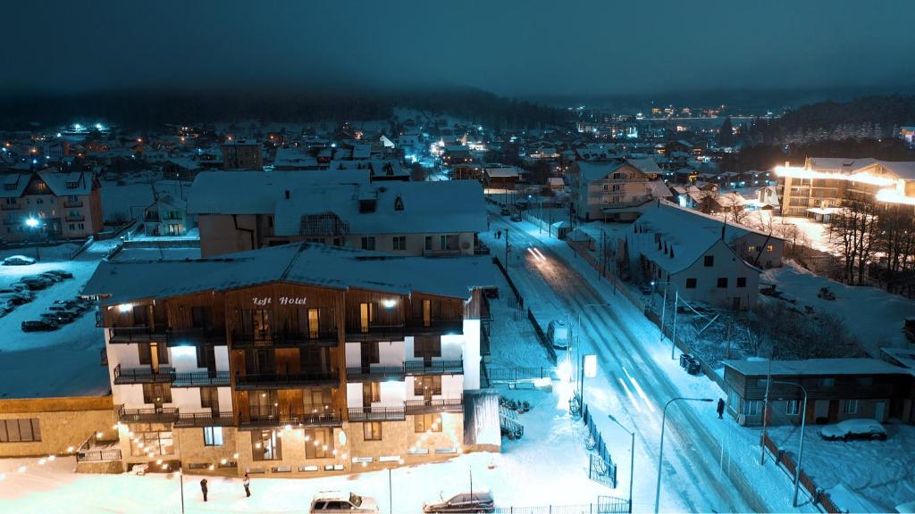 una ciudad iluminada por la noche con edificios cubiertos de nieve en Loft Hotel Bakuriani, en Bakuriani