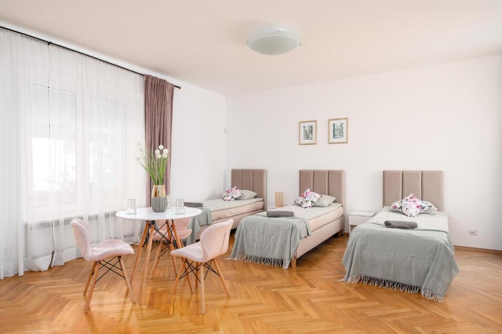Habitación con 2 camas, mesa y sillas en Willa Zacisze - Pokoje Gościnne en Breslavia