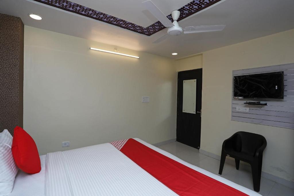 a bedroom with a bed and a black chair at Flagship Richa Grand Inn Near Sahara Ganj Mall in Lucknow
