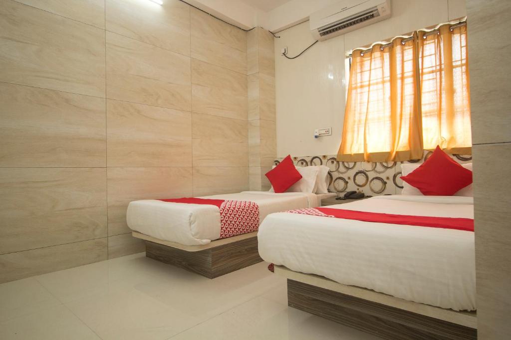 two beds in a room with red and white pillows at Capital O Hotel Priyanshu in Siliguri