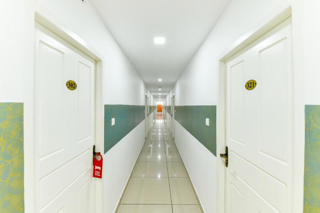 a corridor with white doors in a hallway at Flagship Green Line Residency in Nedumbassery