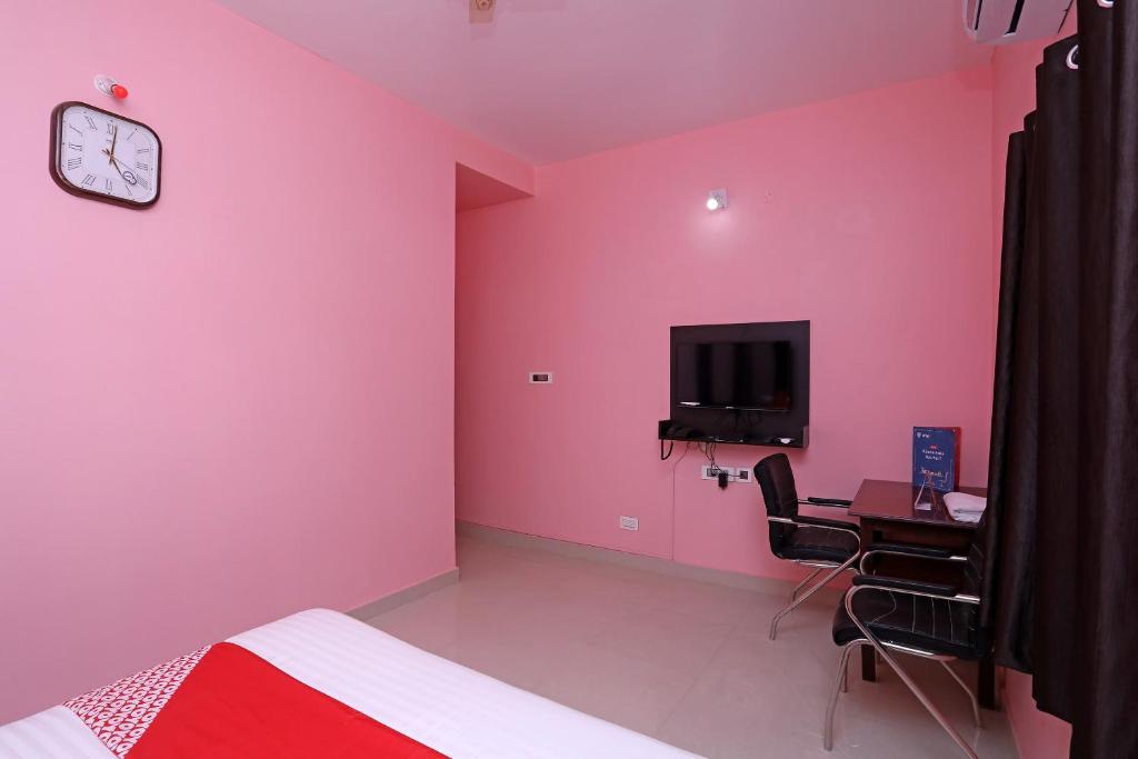 Bārang的住宿－OYO Ms Plaza，粉红色的客房设有书桌和墙上的电视
