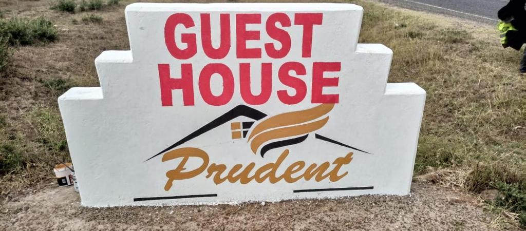 a sign for a guest house on the side of a road at Prudent Guest House in Isuvya