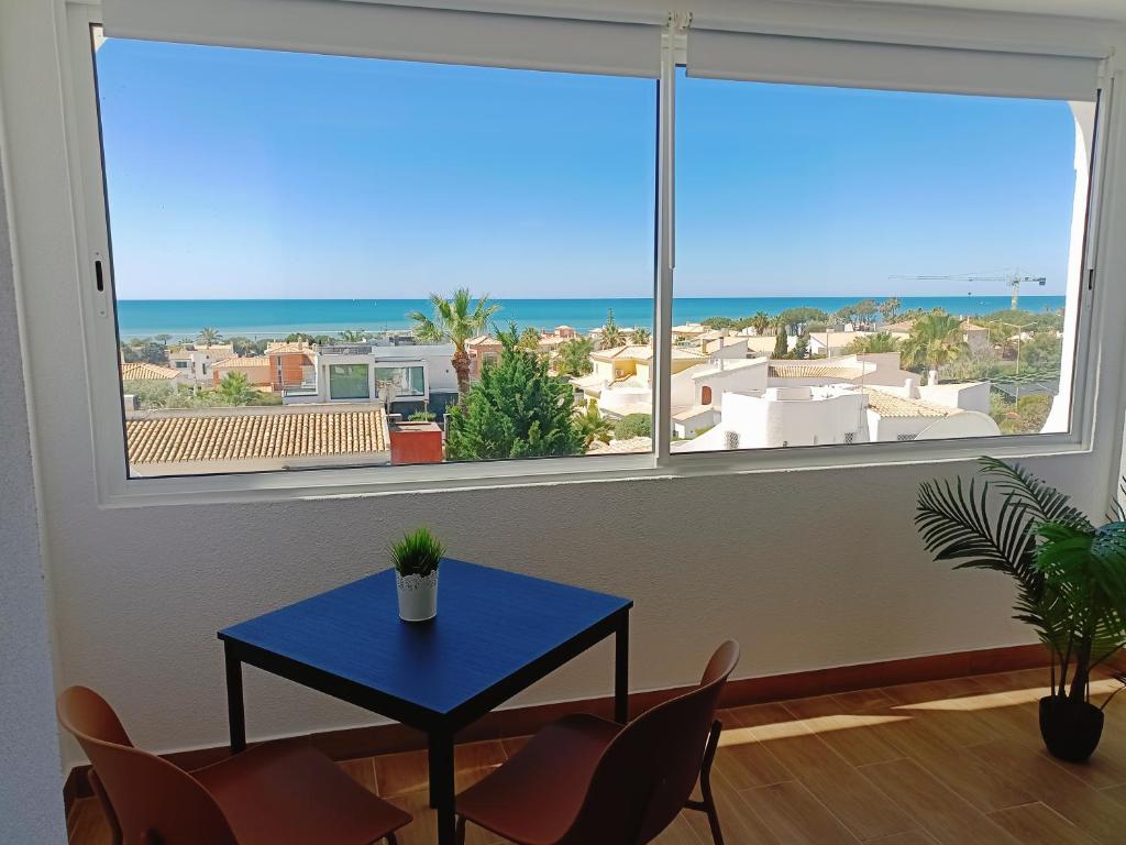 Habitación con una mesa y sillas azules y una ventana grande. en Apartamento Praia da Gale en Albufeira