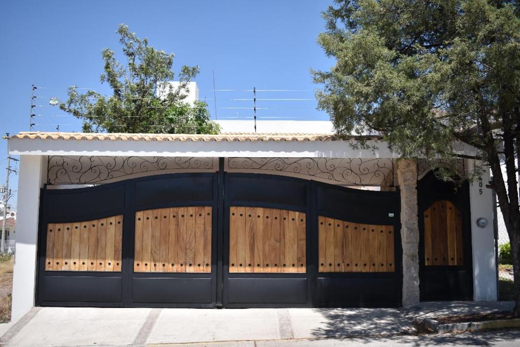 a garage with a black gate and a tree at Loft Montenegro in Aguascalientes