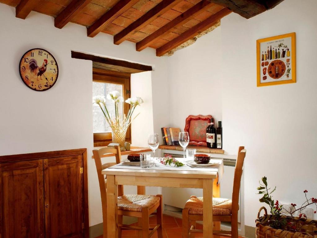 une salle à manger avec une table, des chaises et une horloge dans l'établissement Romantisches Apartment für Paare mit Terrasse und Blick auf den Garten, à San Donato in Poggio
