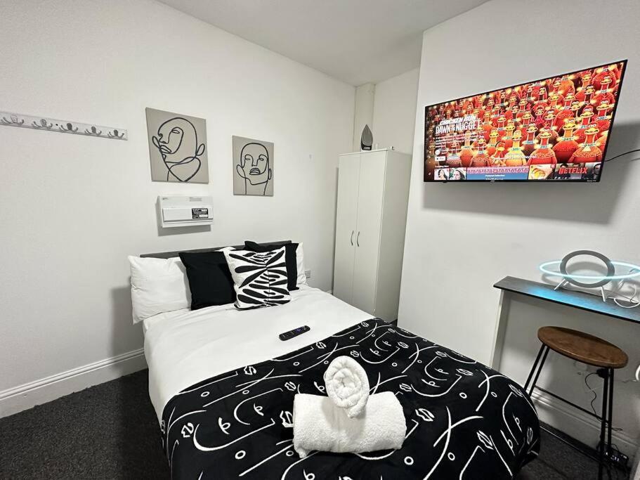 a small bedroom with a bed and a refrigerator at Cosy Chic Flat in the Heart of Kidderminster in Kidderminster