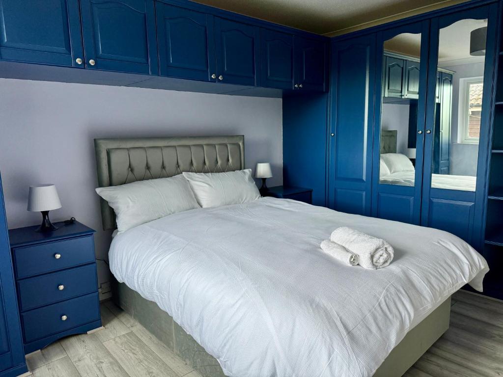 a bedroom with blue cabinets and a bed with two towels at StayViva - Spacoius 3 BR House - Garden, Games Room, Parking near Town Centre and Train station in Bracknell