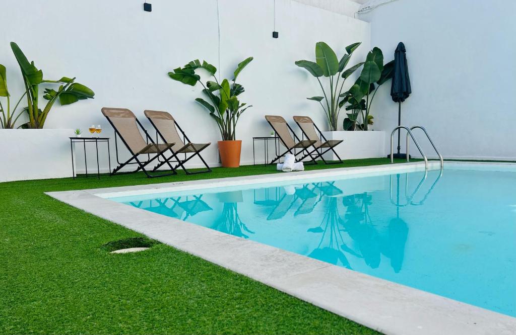 a swimming pool with chairs and grass next to it at La Casa de Carmen in Castilleja de la Cuesta