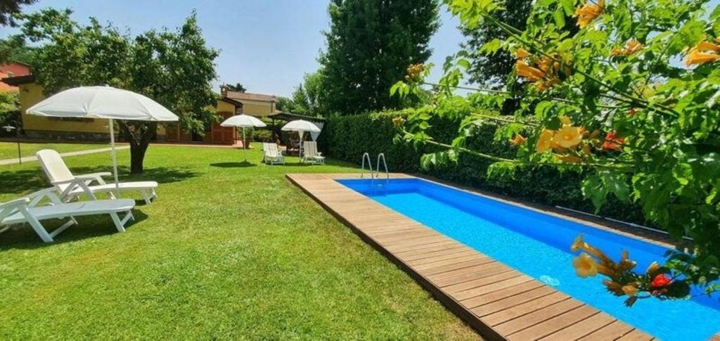 una piscina en un patio con sillas y sombrilla en Ferienhaus mit Privatpool für 2 Personen ca 65 qm in Capannori, Toskana Provinz Lucca, en Capannori