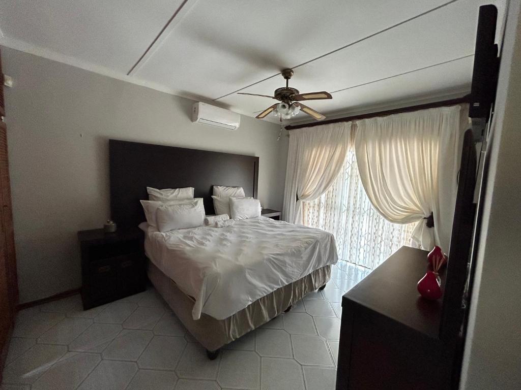 um quarto com uma cama e uma ventoinha de tecto em Zinoma guest house em Empangeni