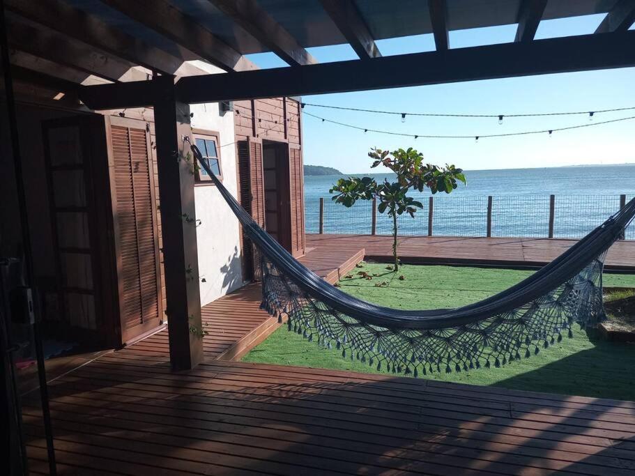 a hammock on a porch with a view of the ocean at Hygge Sunset House in Ilha do Mel