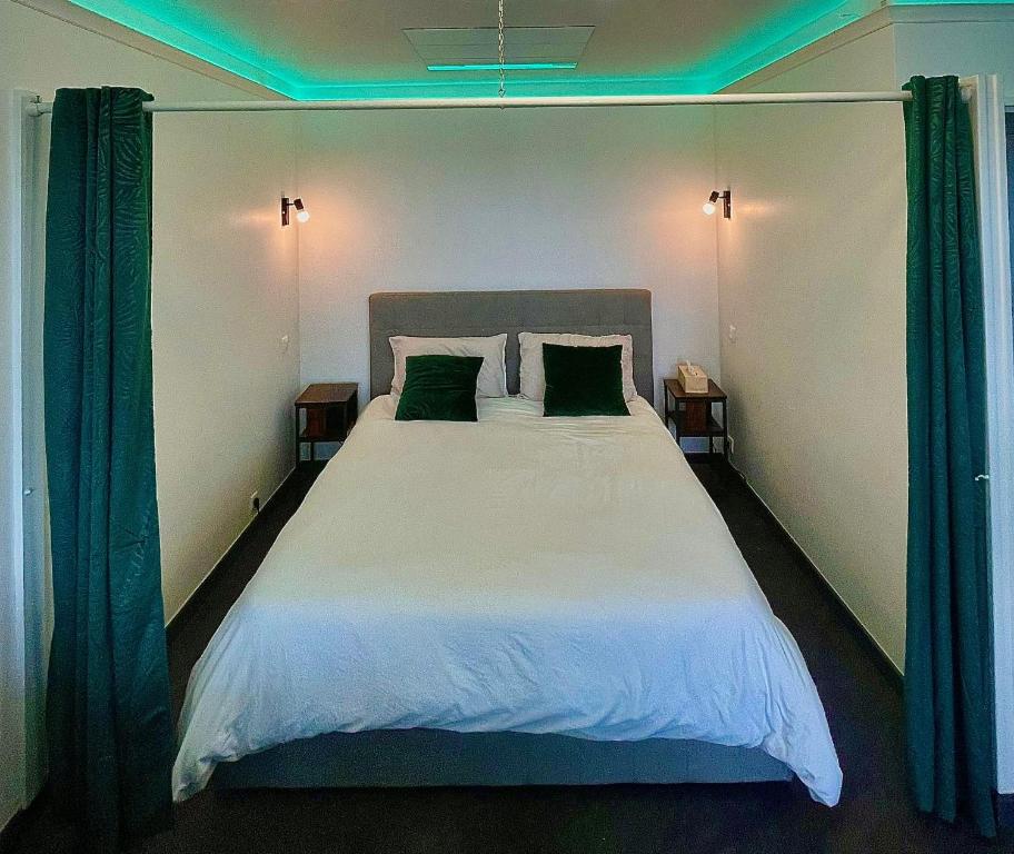 a bedroom with a large white bed with green curtains at L’Escapade SPA Sauna + Jacuzzi in Saint-Brieuc