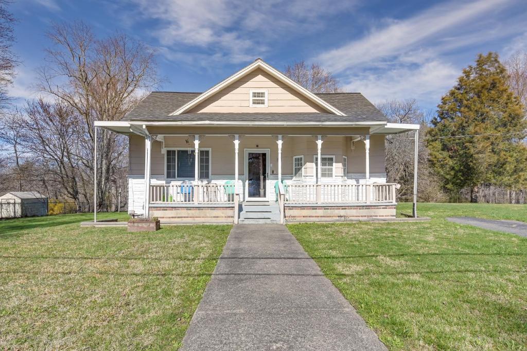 ein weißes Haus mit einer Veranda und einer Liegewiese in der Unterkunft Charming Fayetteville Home with Deck and Grill! in Fayetteville