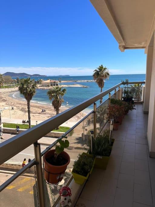 a balcony with a view of a beach with palm trees at Appartement panoramique sur mer in Toulon