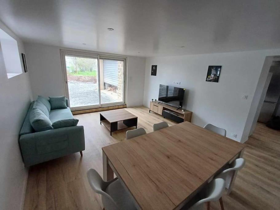 - un salon avec une table et un canapé vert dans l'établissement Agréable maison neuve, à Pontivy