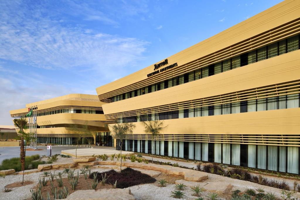 Riyadh Diplomatic Quarter - Marriott Executive Apartments في الرياض: مبنى مكتب مع مبنى اصفر