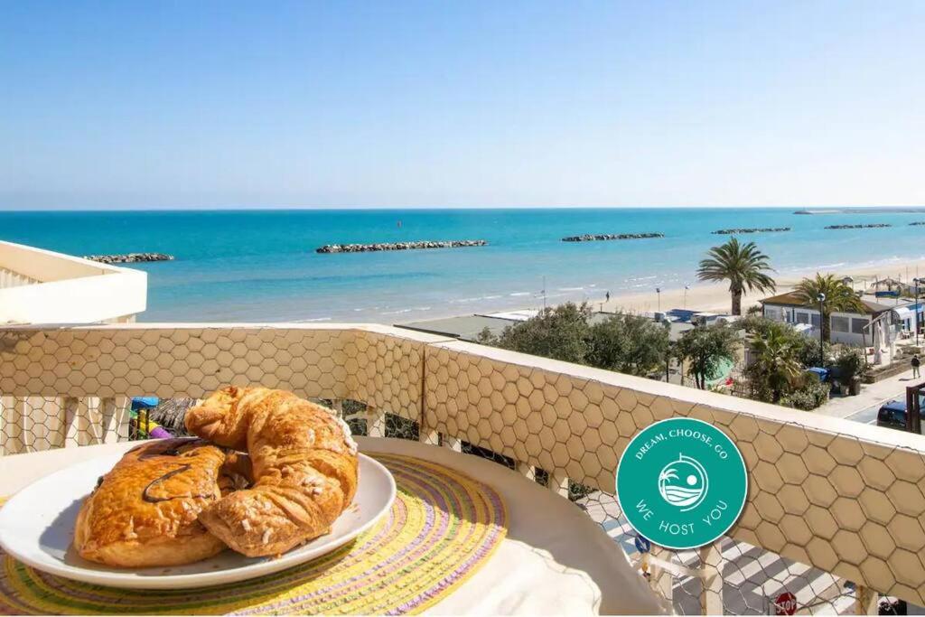 ein Teller Brot auf einem Tisch auf einem Balkon mit Strand in der Unterkunft [Dimora Fronte Mare] Wi-Fi 7 posti Parcheggio in Porto San Giorgio