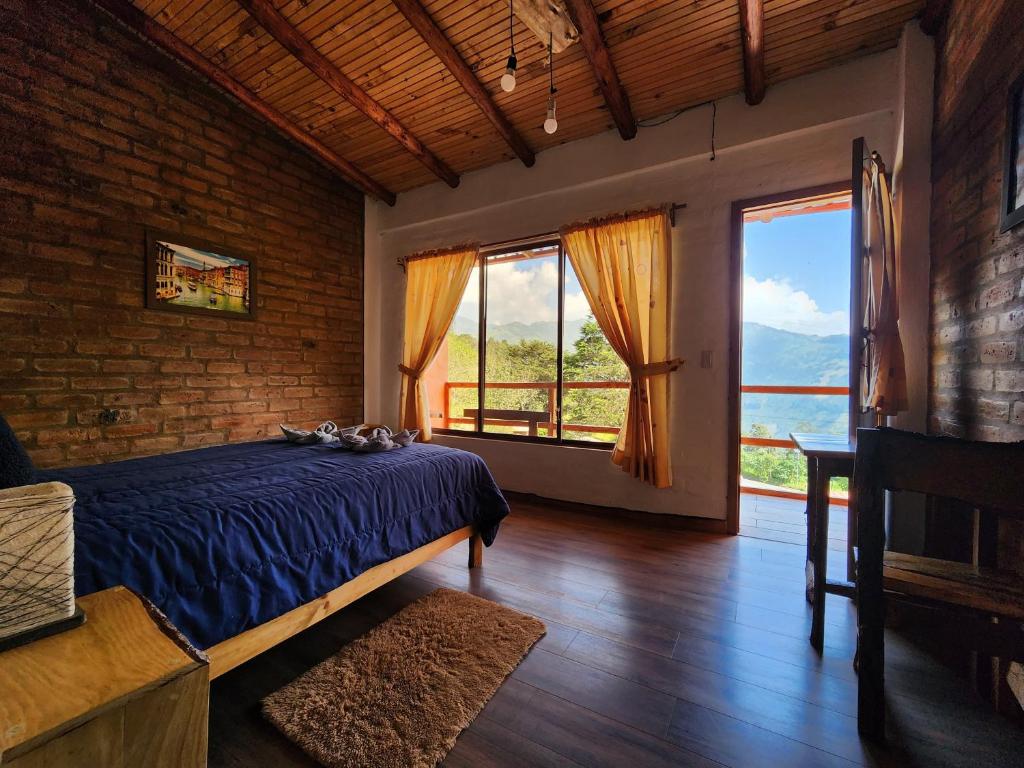 - une chambre avec un lit bleu et de grandes fenêtres dans l'établissement Hotel Pueblo del Mundo, à Baños