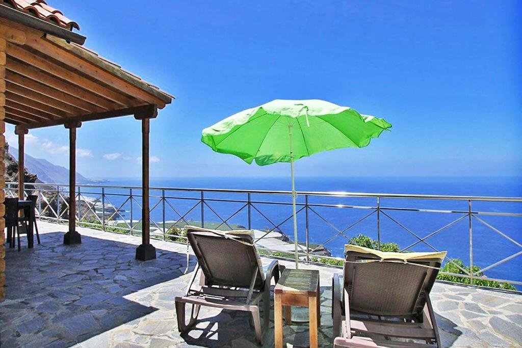 un patio con 2 sillas y una sombrilla verde en Ferienhaus für 4 Personen ca 65 qm in Puerto Naos, La Palma Westküste von La Palma, en Puerto Naos