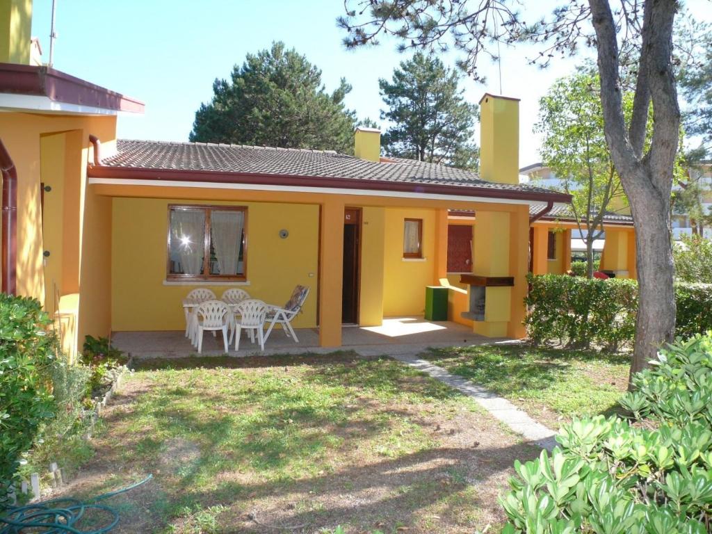 ein kleines gelbes Haus mit einem Tisch und Stühlen in der Unterkunft Ferienhaus für 6 Personen ca 46 qm in Bibione, Adriaküste Italien Bibione und Umgebung in Bibione