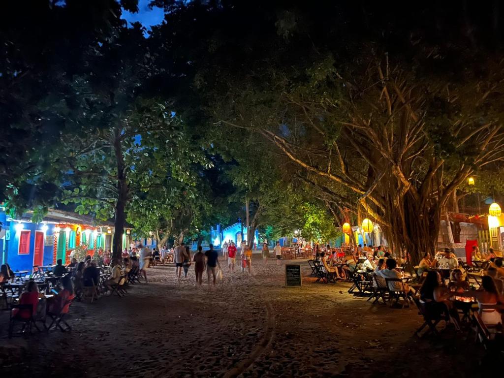 a crowd of people sitting in chairs in a street at night at Pousada Crocodilo Caraíva in Caraíva