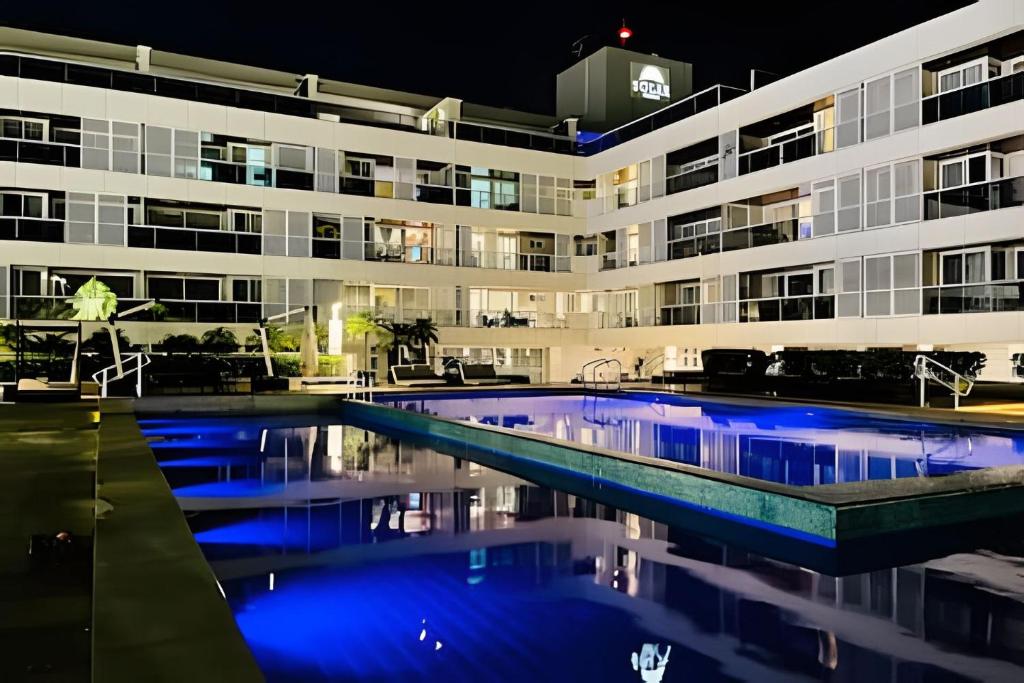 un gran edificio con piscina por la noche en Incríveis apartamentos no Solar Tambaú, en João Pessoa