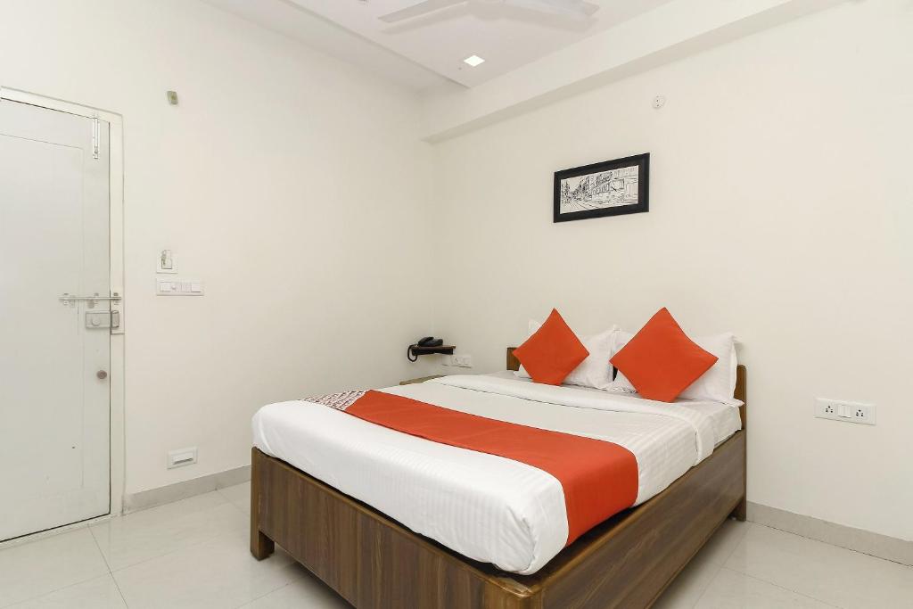 um quarto com uma cama grande e almofadas laranja em Capital O Hotel Green Leaf em Gachibowli