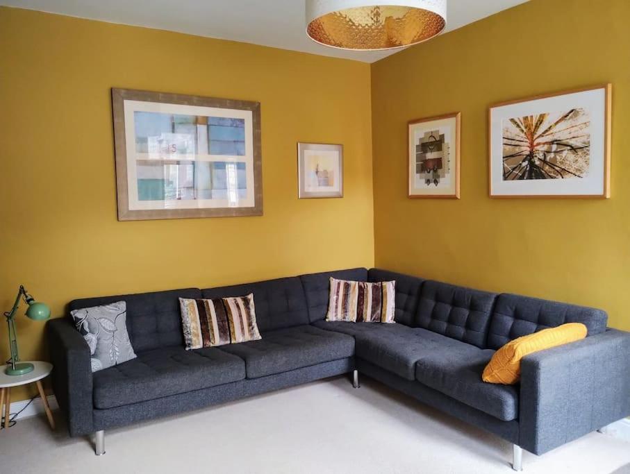 a living room with a blue couch and a yellow wall at The Cobbles - Central, Parking, Netflix & Woodburner in Hebden Bridge