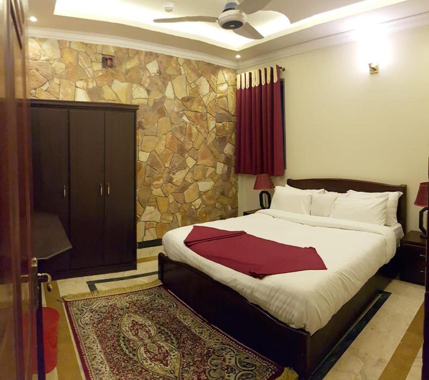 a bedroom with a large bed and a stone wall at Triple One Hotel Suites in Abbottabad